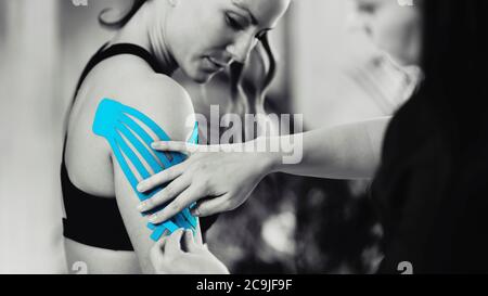 Physical therapist placing kinesio tape on patient's shoulder. Stock Photo