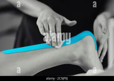 Physical therapist placing kinesio tape on patient's Achilles tendon. Stock Photo