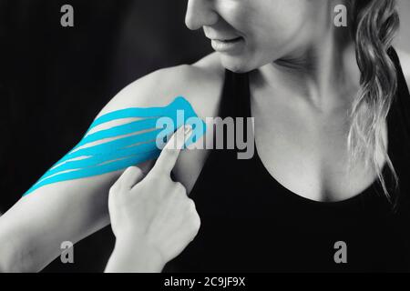 Physical therapist placing kinesio tape on patient's shoulder. Stock Photo