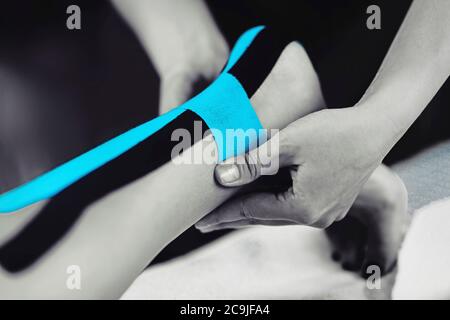 Physical therapist placing kinesio tape on patient's Achilles tendon. Stock Photo
