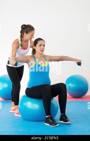 Staying fit in pregnancy. Fitness instructor working with pregnant woman. Stock Photo