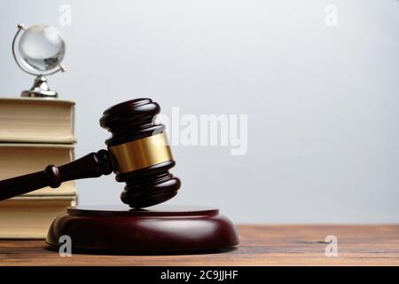 Judge hammer with books and small glass globe on white background. Stock Photo