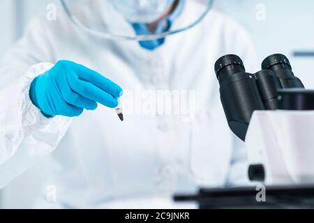 Ancient DNA analysis. Female scientist holding micro tube with sample in ancient DNA laboratory. Stock Photo