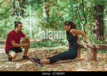Young couple exercising outdoors, in park.