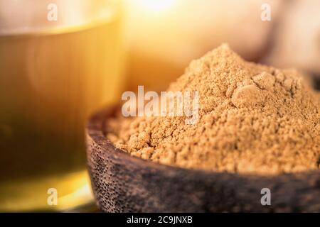 Ginger ground spice powder in wooden bowl, ginger tea and fresh ginger root on the table. Anti-inflammatory herbal medicine. Stock Photo