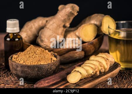 Sliced ginger root and ginger powder in the bowl on the table. Anti-inflammatory herbal medicine. Stock Photo