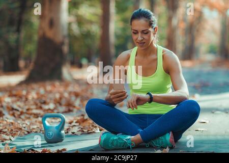 Woman checking progress on smart watch after outdoor training. Stock Photo