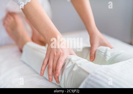 Marma knee therapy. Close-up of Ayurveda practitioner's hands treating left and right patient Janu Marmas. Acupressure points for knee pain. Stock Photo