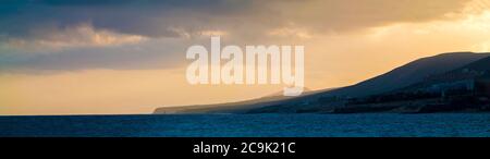 Sun setting behind mountains. Stock Photo