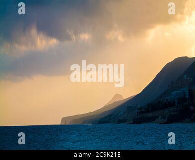 Sun setting behind mountains. Stock Photo