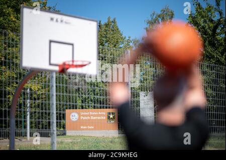 Stuttgart, Germany. 31st July, 2020. A man plays basketball in front of a sign pointing to the main entrance of the US barracks 'Patch Barracks'. The Patch Barracks also houses the headquarters of the US European Command (EUCOM). According to an announcement by US President Trump, this is to be moved from Stuttgart to Mons in Belgium. Credit: Sebastian Gollnow/dpa/Alamy Live News Stock Photo
