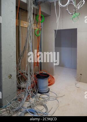 on a construction site many network and power cables hang from the ceiling Stock Photo