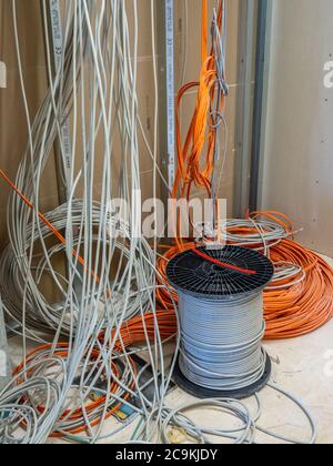 on a construction site many network and power cables hang from the ceiling Stock Photo