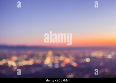 An abstract blurry image of a city skyline at sunset, featuring round bokeh balls from the twinkling lights below Stock Photo