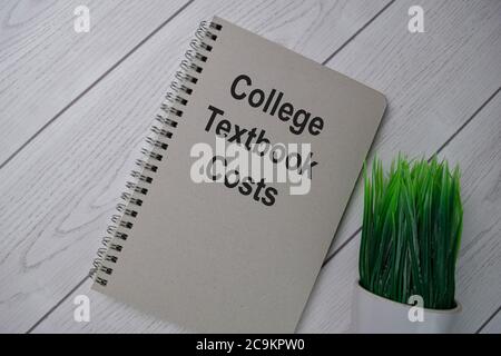 Book about College Tectbook Costs isolated on wooden table. Stock Photo