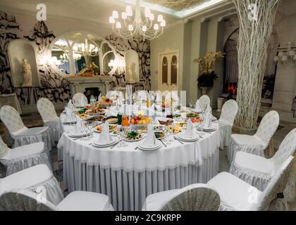 Beautifully decorated festive table with plates and glasses and a bouquet of flowers in a restaurant Stock Photo