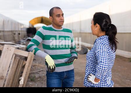 Young man and woman workers talking near wooden pallets outdoors Stock Photo