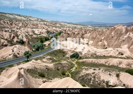 A road winds through the incredible volcanic rock formations known as fairy chimneys in the Devrent Valley in the Cappadocia region of Turkey. Stock Photo