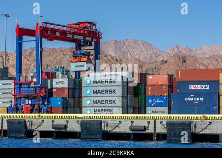 A huge cranes unloads shipping containers from a  ship docked at the Aqaba Container Terminal on the Gulf of Aqaba in Jordan. Stock Photo
