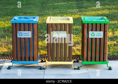 Recycling bins of different colors (yellow, green, blue) outdoors. Garbage bin in the park, trash can on green grass background. Waste sorting concept Stock Photo