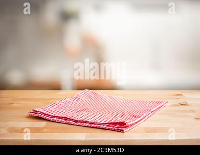 Red fabric,cloth on wood table top on blur kitchen counter (room)background.For montage product display or design key visual layout. Stock Photo