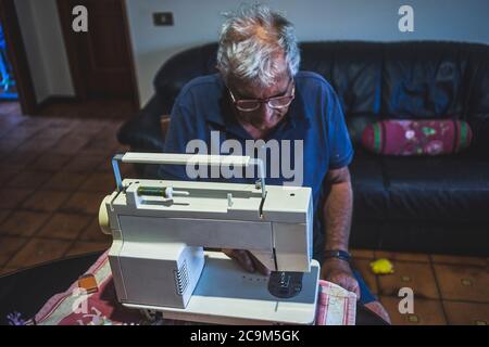 elderly man using a sewing machine Stock Photo