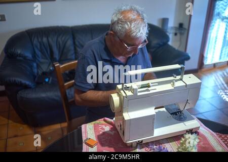 elderly man using a sewing machine Stock Photo