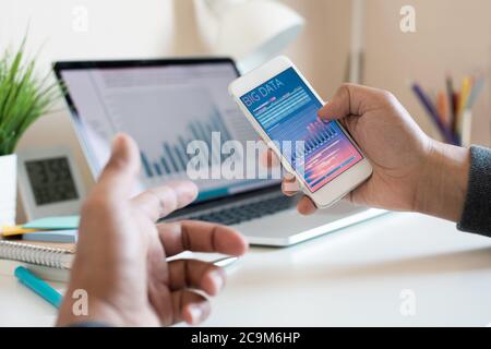Big data or digital marketing or concepts with young person watching data graph on smartphone and laptop.business research Stock Photo