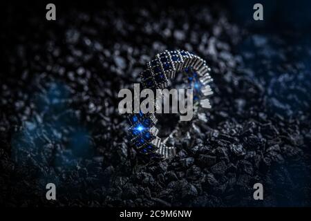 Silver ring with blue stones on black coal background Stock Photo
