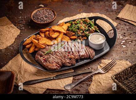 Juicy steak medium rare beef with green salad and fried potatoes Stock Photo