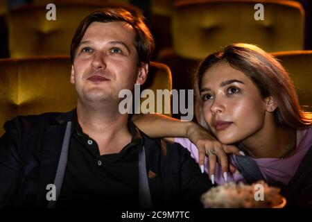 Man whispering to his girlfriend at the cinema Stock Photo