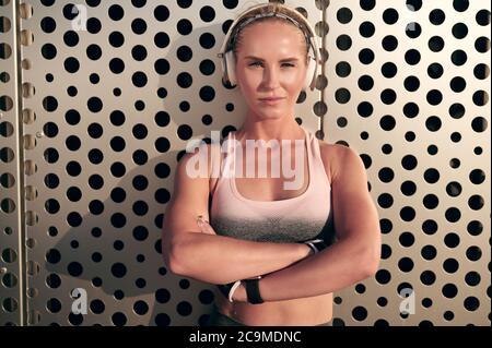 Athletic woman crossed her arms over her chest and listens to music on headphones. Stock Photo