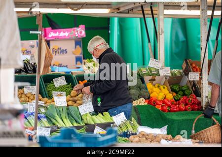 Richmond, North Yorkshire, UK - August 1, 2020: A mature man with hearing aid wearing a protective face mask shopping at an outdoor fruit and veg mark Stock Photo