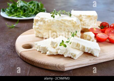 Delicious healthy sheep or goat feta cheese. Chunks of cheese on a wooden board. Stock Photo