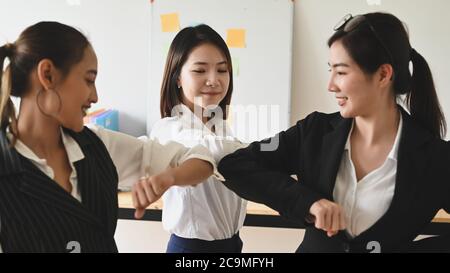 Women are greeting each other with the elbow. Elbow bumps greeting style to prevent contact and virus spread. Stock Photo