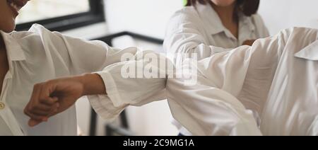 Closeup women are greeting each other with the elbow. Elbow bumps greeting style to prevent contact and virus spread. Stock Photo