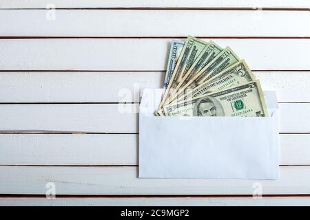 Cash in an envelope, the denomination on a table from white wooden boards. Stock Photo