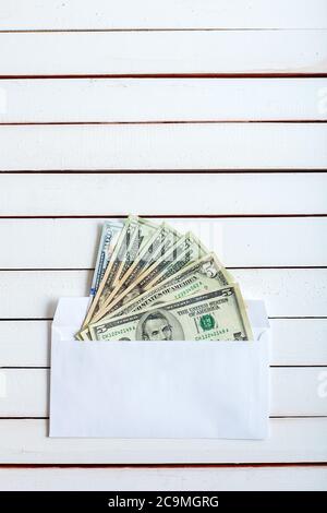 Cash in an envelope, the denomination on a table from white wooden boards. Stock Photo