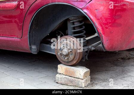 Car without wheels costs on brick, old rusty car brakes in poor condition. Stock Photo