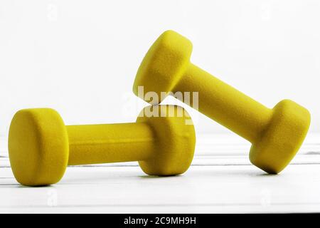 dumbbells weight for fitness  yellow color on white wooden board. Stock Photo