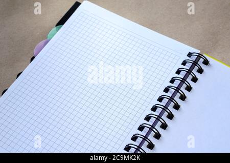 Open spring-bound notebook. White blank page and squared page. Top view at an angle. Selective focus. Stock Photo