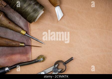 Leather craft tools on old wood table. Leather craft workshop. Stock Photo
