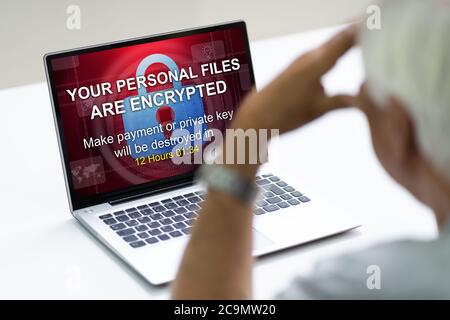 Elder Man With Ransom Text On Laptop Monitor After Ransomware Cyber Attack Stock Photo