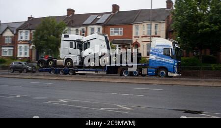 A Johnson haulage lorry carrying two trucks on trailer traveling on Millbrook road Southampton towards Southampton Docks. Stock Photo