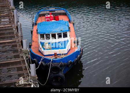 Old fishing boat docking at the pier. Vibrant orange and Blue. Rusty. Stock Photo