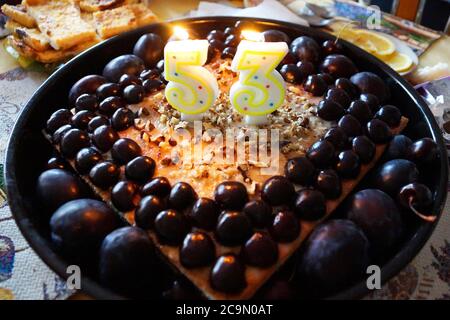 number 53 from candles on a fruit cake with cherries and plums Stock Photo