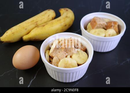 Uncooked Ingredients Ready for Baking Banana Bread Pudding in a Small Ceramic Baking Bowl Stock Photo