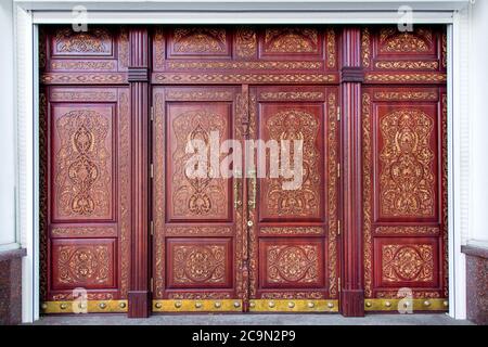 Wood carving door traditional Uzbek pattern, claret color with golden inserts. Stock Photo