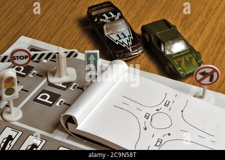 Notepad, book of traffic rules, toy cars, traffic lights and stop sign on a desk table. Studying and preparing for driving test Stock Photo