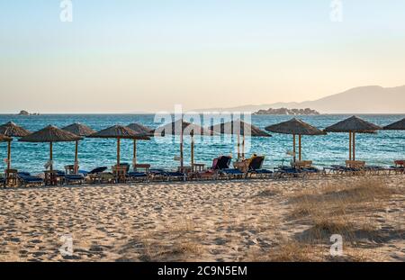 View of Plaka beach, with sunbeds and umbrellas, in the afternoon. Naxos island, Greece Stock Photo